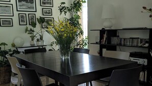 Un coin repas avec une table en bois foncé, des chaises noires, un vase rempli de fleurs jaunes et des tableaux encadrés accrochés au mur.