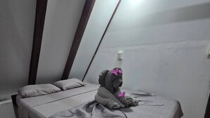 Una habitación con una cama, una mesita y un enchufe.