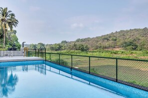 Ein Swimmingpool mit Blick auf eine grüne Landschaft und eine Hügelkette in der Ferne.