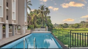 A swimming pool with a view of a building and palm trees. - 2bhk With Pool nr Candolim Beach Palms By Umiya (Candolim)