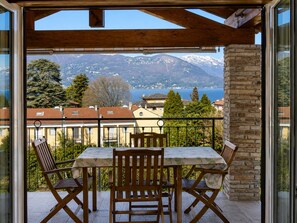 A balcony with a table and chairs, overlooking a mountainous landscape and a lake. - Elegant Lakeview Apartment for 6 (Germignaga)