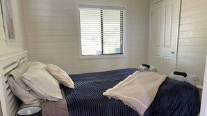 Un dormitorio con cama, ventana, lámpara y puerta.