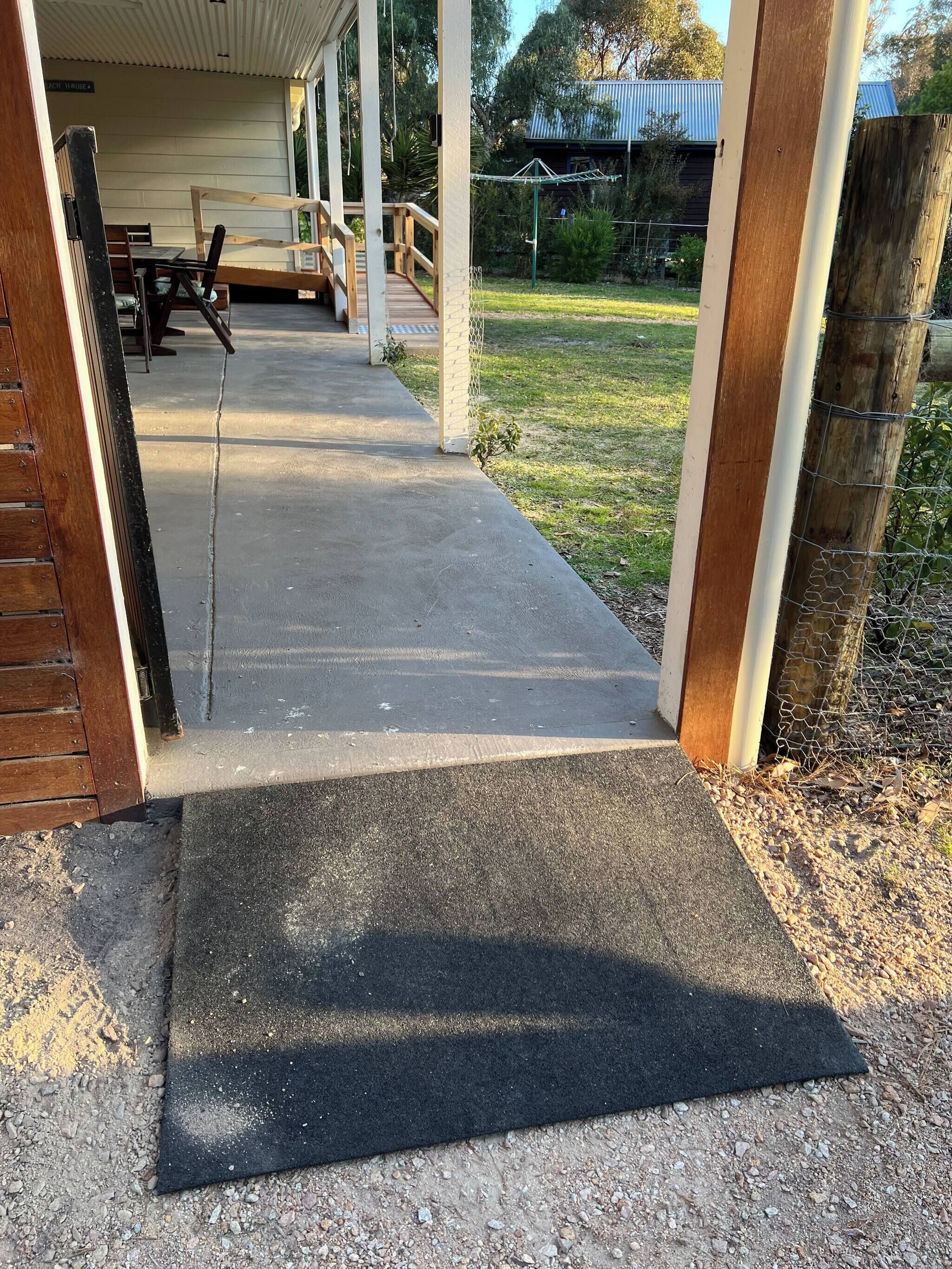 A covered outdoor area with a concrete pathway leading to a wooden deck.