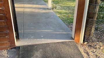 A covered outdoor area with a concrete pathway leading to a wooden deck.