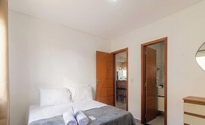 Ein Schlafzimmer mit einem Bett, zwei Türen, einem Spiegel und einer Kommode.
