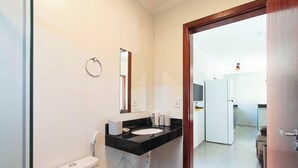 Une salle de bain comprenant des toilettes, un lavabo, un miroir et un porte-serviettes.