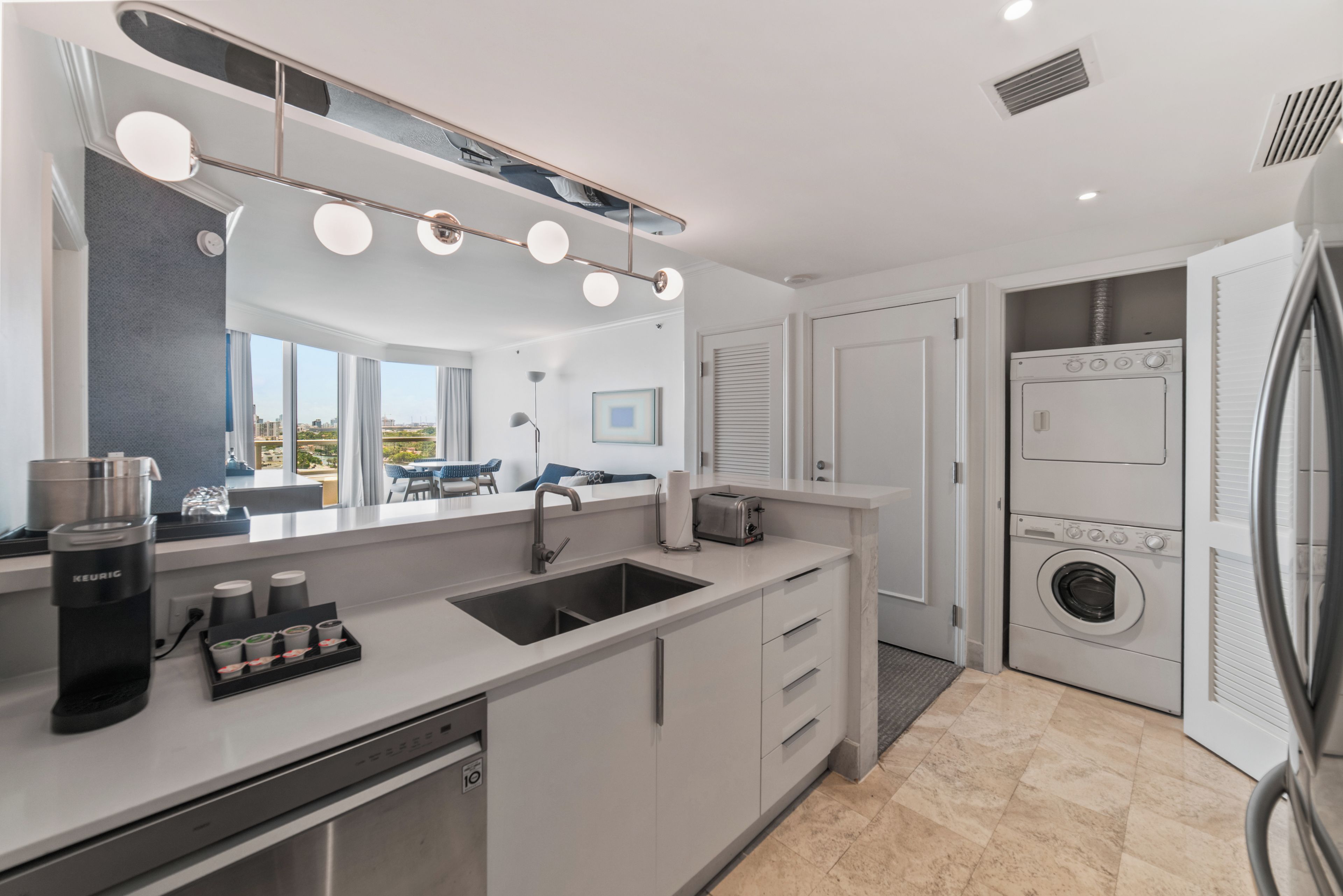 A modern kitchen with a sink, coffee maker, and a built-in washing machine.