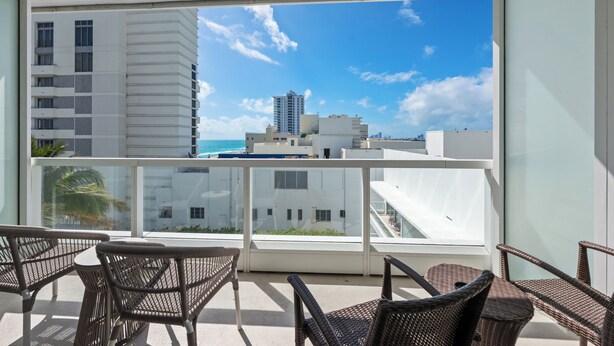 A balcony with wicker furniture and a view of a cityscape and ocean. - Fontainebleau Miami Resort (Miami Beach)