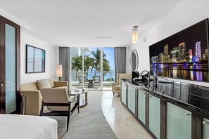 A modern hotel room with a balcony, a dining area, and a large cityscape view. - Fontainebleau Miami Resort (Miami Beach)