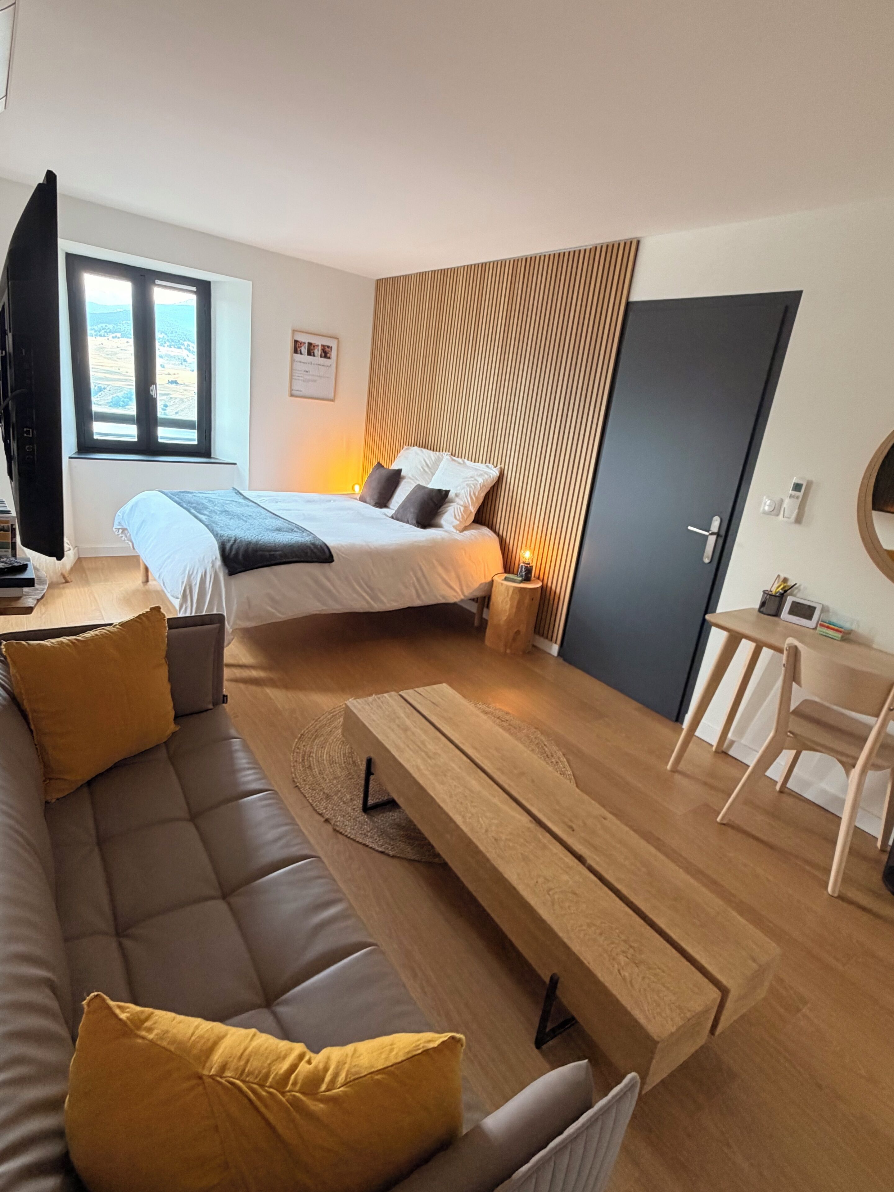 Une chambre moderne avec un lit, un canapé, une table en bois et un bureau.