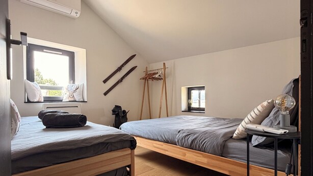 Una habitación con una cama tipo altillo, un escritorio con una lámpara y una ventana pequeña.