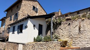 Un edificio de piedra con fachada blanca, un balcón y un muro de piedra.