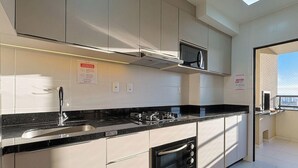 A modern kitchen with stainless steel appliances, a black countertop, and a window providing natural light. - Modern Apartment in Cond. With Pool Skl1505 (Penha)