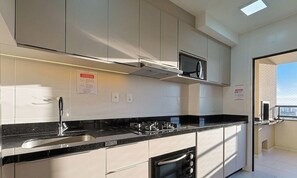 Une cuisine moderne dotée d’appareils électroménagers en acier inoxydable, d’un plan de travail noir et d’un four encastré.