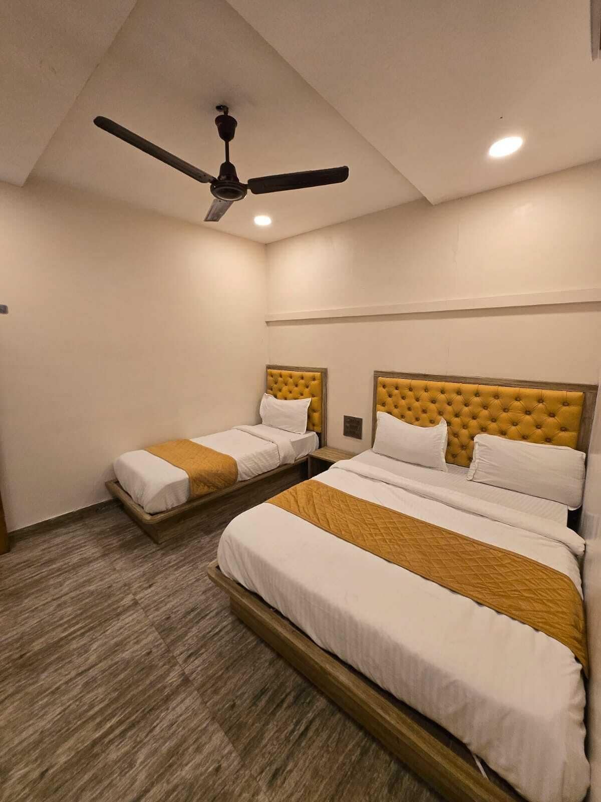 A hotel room with two beds, a ceiling fan, and a wooden floor.