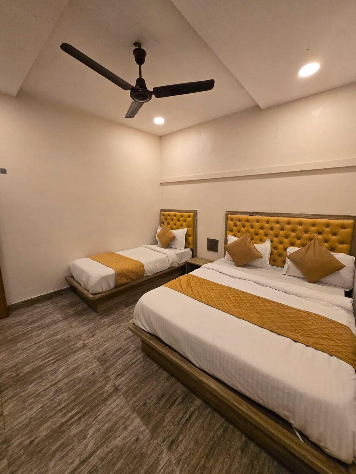 A hotel room with two beds, a ceiling fan, and recessed lighting.