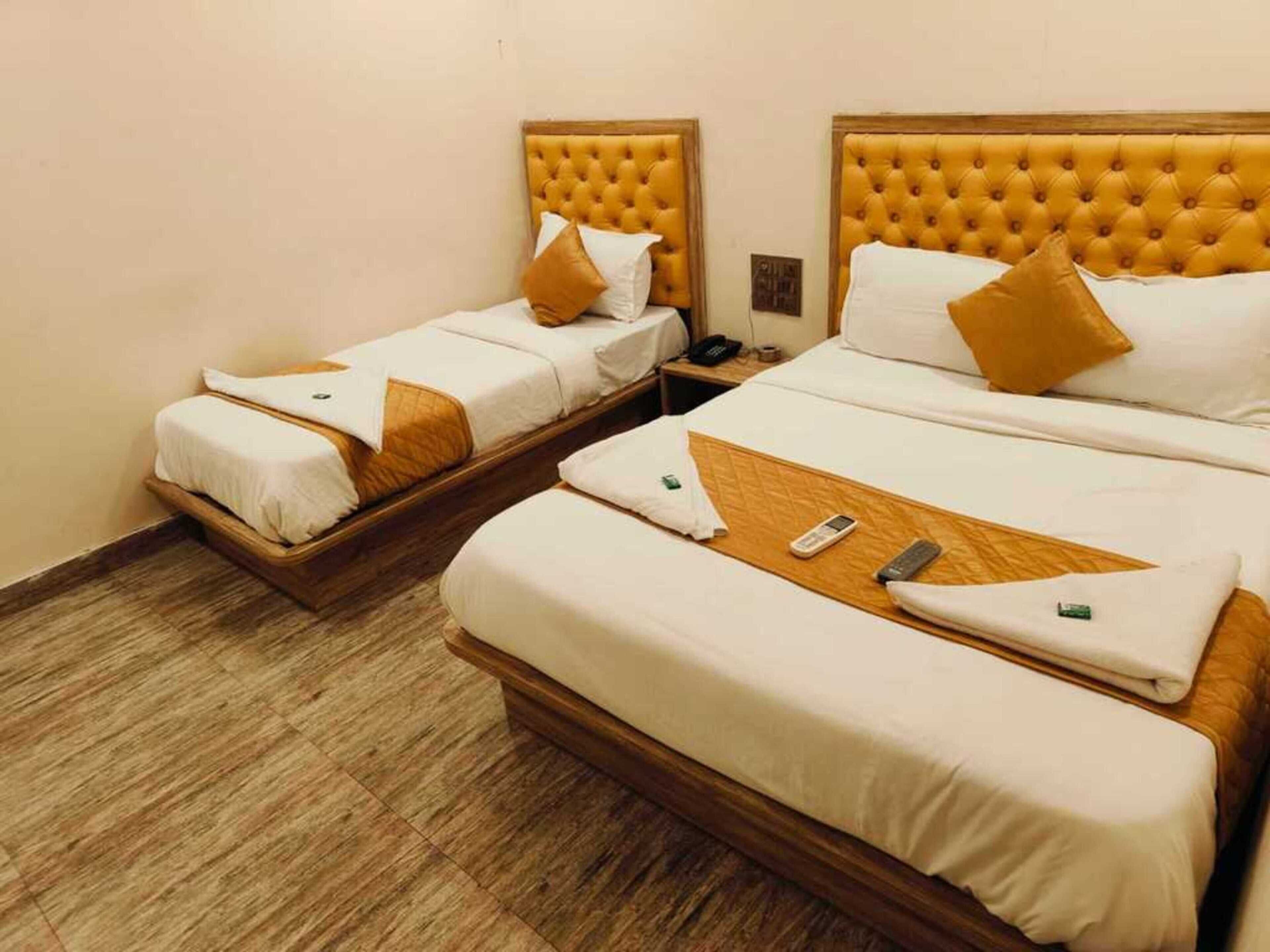 A hotel room with two beds, each with a wooden headboard and white bedding. There is a telephone on the nightstand next to the beds.