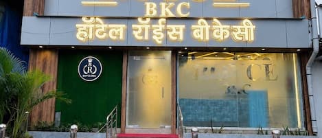 A hotel entrance with a red carpet, a sign reading 'HOTEL ROYCE BKC', and a logo with a crown.