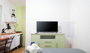 A small room with a bed, a desk with a computer monitor, a microwave, and a chair. - Studio nr. Rio Vermelho Beach Ram0003 (Salvador)