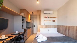 Ein Hotelzimmer mit einem Bett, einem Schreibtisch mit Stuhl, einem Fernseher und einer Küchenzeile.