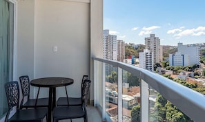 Un balcón con una mesa y sillas, con vistas a un paisaje urbano con rascacielos.