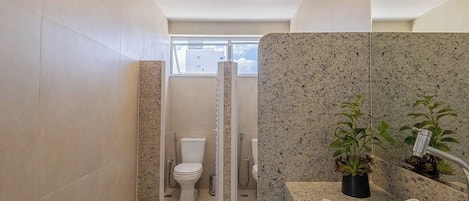 Een moderne badkamer met douche, toilet en wastafel.