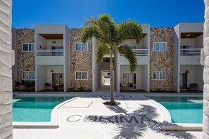 Um edifício moderno com piscina, fachada de pedra e varandas.