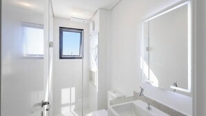 Et moderne badeværelse med brusebad, toilet og håndvask.