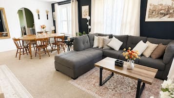 A living room with a sectional sofa, a dining table with chairs, and a coffee table.