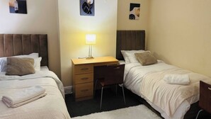 A hotel room with two beds, a desk, and a chair. - Room-home Away From Home in Salford (Salford)