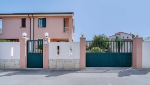 Una propiedad residencial privada con un edificio de dos pisos, un muro de piedra y cielo despejado.