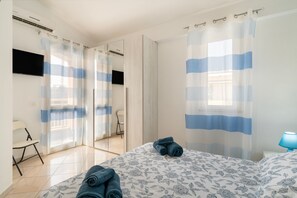 Una camera d'albergo con un letto, una sedia, una scrivania e uno specchio.