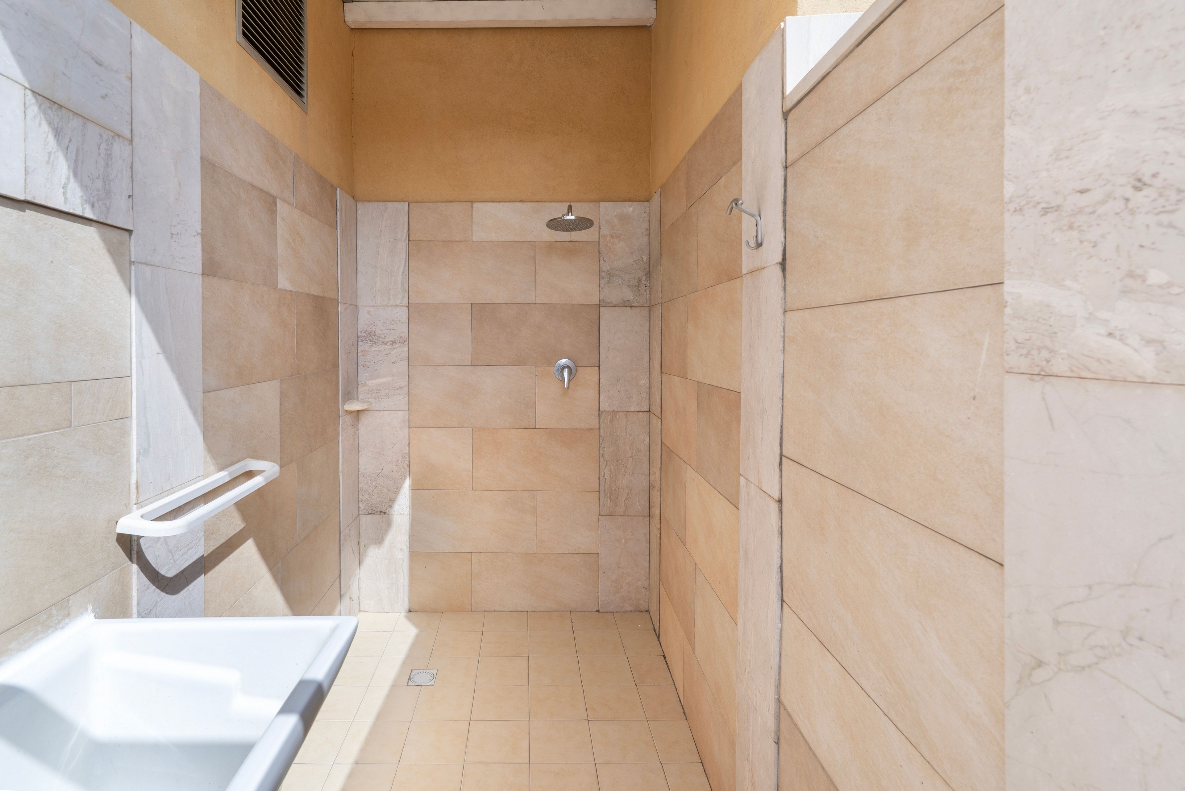 Un espacio de ducha estrecho con bañera, ducha y barandilla.