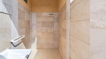 Un espacio de ducha estrecho con bañera, ducha y barandilla.
