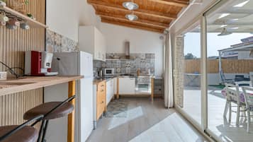 Eine moderne Küche mit Holzboden, einem Einbauofen, einer Mikrowelle und einem Essbereich mit Tisch und Stühlen.