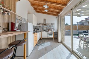 Una cucina moderna con soffitto in legno, forno integrato, microonde e zona pranzo con tavolo e sedie.