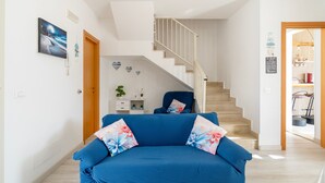 Una sala moderna con un sofá azul, una escalera y vistas del área de estar.