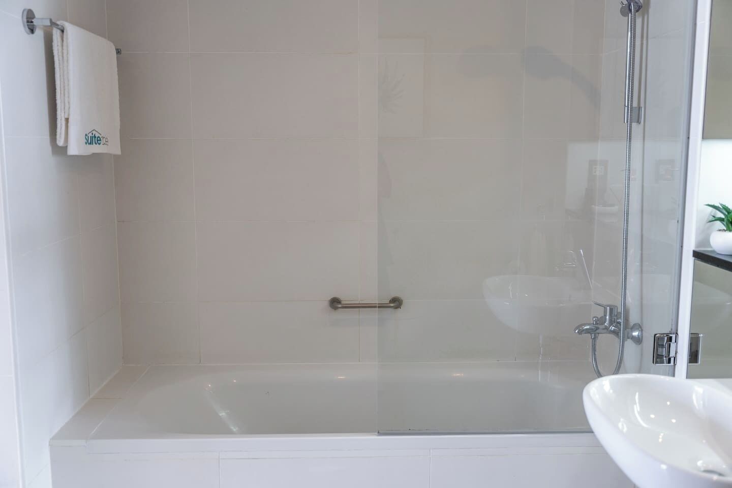 A modern bathroom with a glass-enclosed shower, a white bathtub, and a sink.