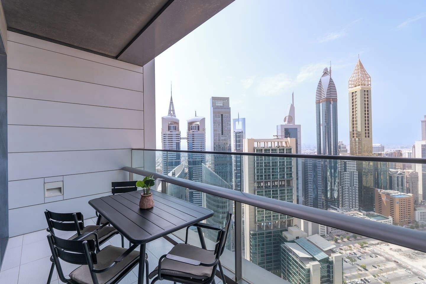 Ein Balkon mit Tisch und Stühlen, mit Blick auf eine Stadtlandschaft mit modernen Wolkenkratzern.