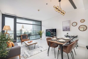 A modern living room with a dining area, large windows, a flat-screen TV, and a city view. - Bright and central Index Tower DIFC by Suiteable (Dubai)