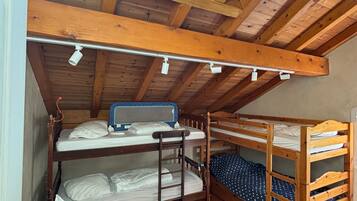 A dormitory-style room with bunk beds, a skylight, and a wooden ceiling.