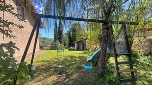 Takapihalla on leikkikehä, liukumäki ja puu.