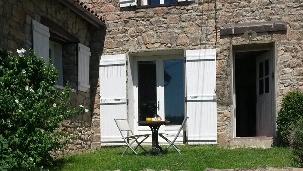 Een stenen gebouw met een klein terras, een tafel en stoelen.