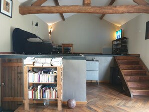 Ein gemütliches Wohnzimmer mit einer Couch, einem Holzregal, einem kleinen Tisch und einer Treppe, die in eine obere Etage führt.