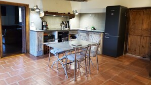 Een keuken met een eettafel, stoelen, een koelkast en een houten kast.