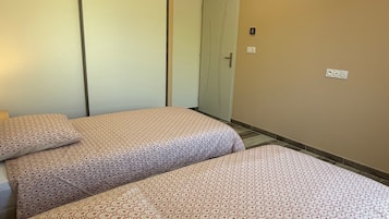 Habitación de hotel con dos camas, un armario, una puerta y un interruptor de luz en la pared.