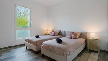 A double room with two beds, a window with a view of greenery, and bedside lamps.