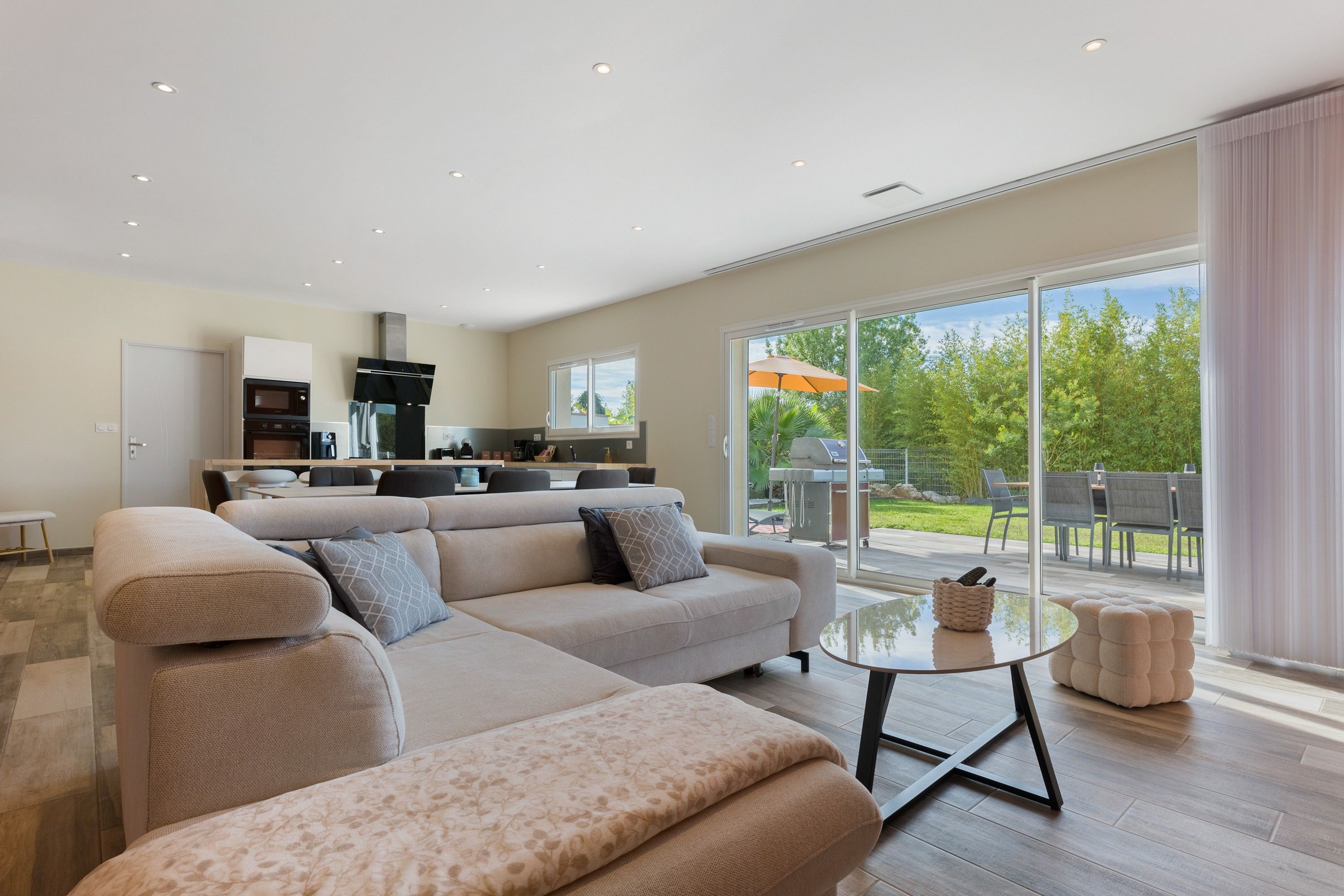 A modern living room with a sofa, a coffee table, and a kitchen in the background.