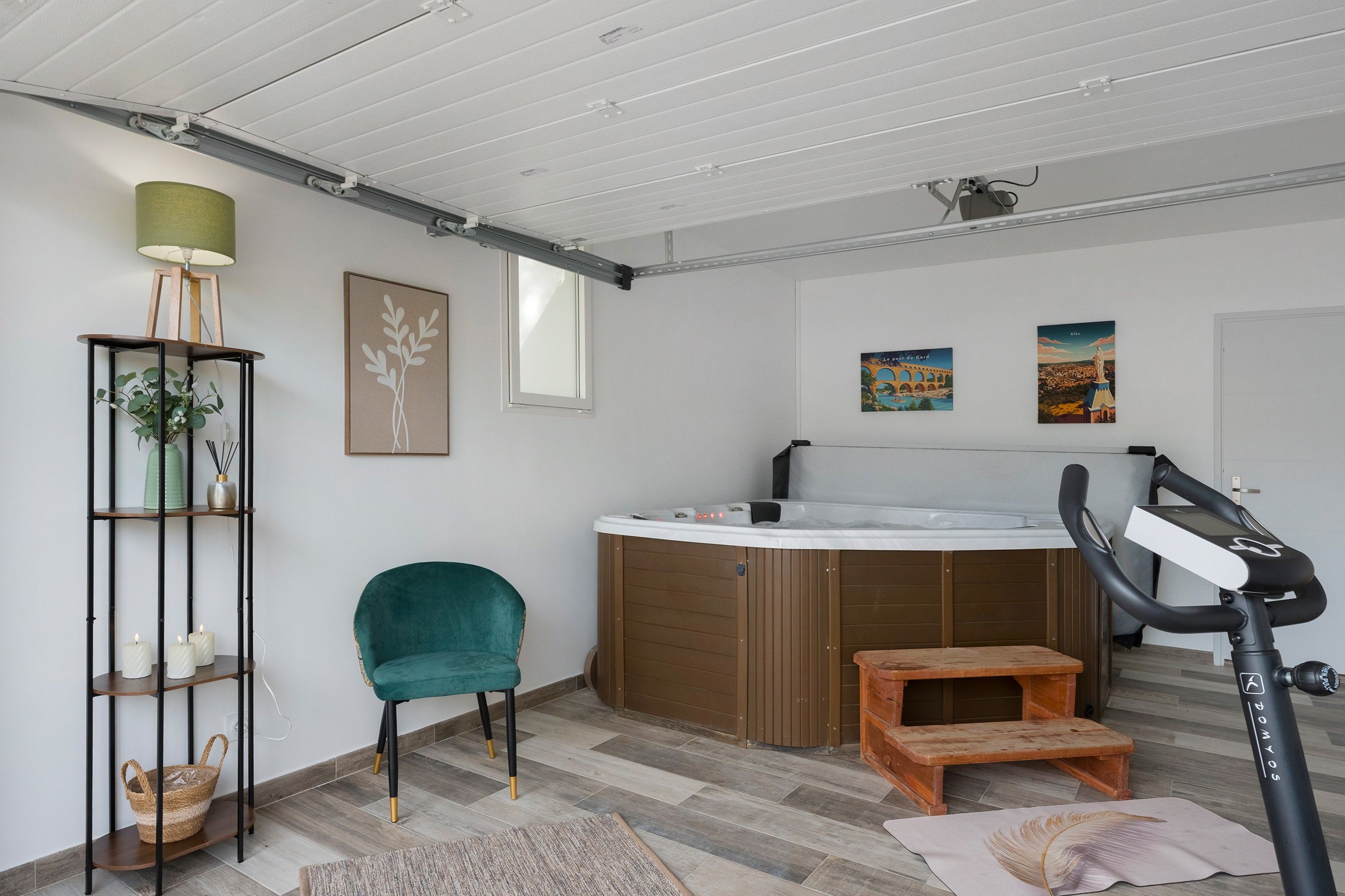 A modern room with a hot tub, exercise equipment, a chair, and artwork on the walls.