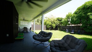 A covered patio with two rocking chairs, a table, and a green pool table.
